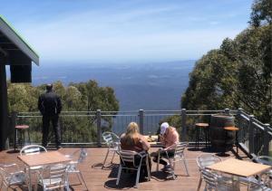 two people sitting at tables on a deck with a view at Altitude Apartment 2 in Baw Baw Village