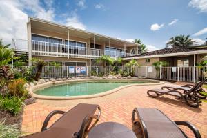 a house with a swimming pool with chairs and a building at Comfort Inn Cairns City in Cairns