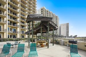 un patio con sillas y una mesa frente a un edificio en Phoenix 7 Unit 1110 en Orange Beach