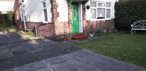 a house with a green door and a bench in the yard at Green Village Guest House - Near Manchester Airport in Sale