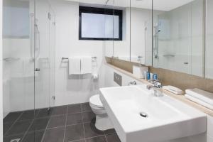 a bathroom with a toilet, sink, and shower at Meriton Suites Pitt Street, Sydney in Sydney