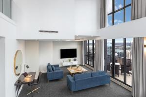 a living room filled with furniture and a tv at Meriton Suites Pitt Street, Sydney in Sydney