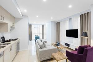 a kitchen and living room with purple chairs and a tv at Meriton Suites Pitt Street, Sydney in Sydney