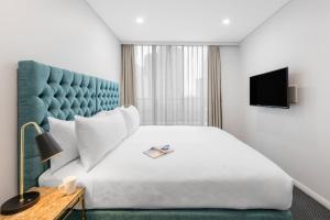 a hotel room with a bed and a television at Meriton Suites Pitt Street, Sydney in Sydney