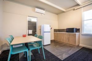 a kitchen with a table and a refrigerator at Nightcap at Sandbelt Hotel in Moorabbin