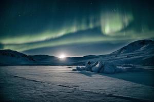an image of the aurora dancing in the sky at isi4u hostel, dogsled, snowmobiling in Sisimiut