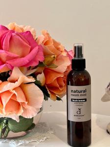 a bottle of natural room mist next to a vase of flowers at Birchwood Cottage in Yarck