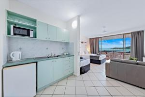 a kitchen with blue cabinets and a living room with a couch at Ocean View 33A Studio Pool Ocean View WIFI in Airlie Beach