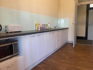 a kitchen with white cabinets and a microwave at Imperial Hotel Coonabarabran in Coonabarabran