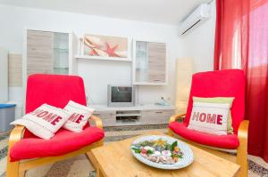 ein Wohnzimmer mit 2 roten Stühlen und einem Tisch in der Unterkunft Apartment Toni&Tina in Vela Luka