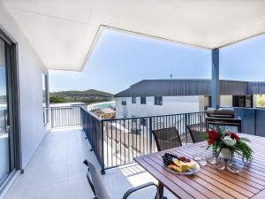 a balcony with a table with flowers on it at Fingal Bay Seabreeze Unit 2 16 Tuna Crescent in Fingal Bay
