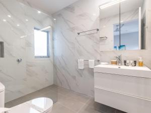 a white bathroom with a toilet and a sink at Fingal Bay Seabreeze Unit 2 16 Tuna Crescent in Fingal Bay