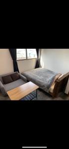 a bedroom with a bed and a couch and a window at コンドミニアムホテル Stay inn Blue in Hukue