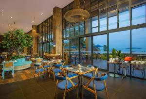 Swiss-Belresort Belitung في Tanjungbinga: مطعم بطاولات وكراسي ونوافذ