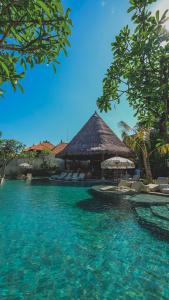 a resort with a pool with chairs and a building at Amnaya Resort Nusa Dua in Nusa Dua
