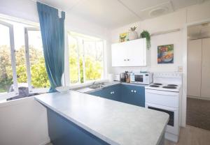 una cocina con armarios azules y un horno de fogón blanco en Cabana - Original Straddie Beach Shack, en Point Lookout