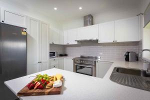 Redims Hill Cottage في نولكابا: مطبخ مع دواليب بيضاء وطاولة تقطيع مع فواكه