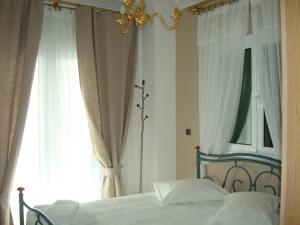 a bedroom with a bed with white curtains and a chandelier at Merlot Village Rental Apartments in Kariá