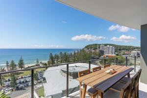a balcony with a wooden table and a view of the ocean at Ambience on Burleigh Beach in Gold Coast