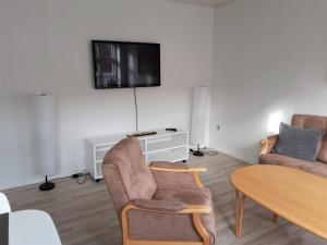 a living room with two chairs and a tv on the wall at Latinerkvarteret in Viborg