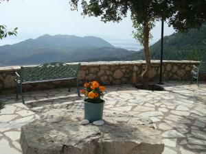 a vase of flowers sitting on a rock next to a bench at Merlot Village Rental Apartments in Kariá