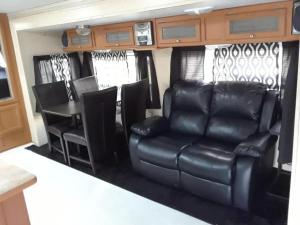 a rv with a black leather couch and chairs at Confort y Relajacion in Vega Alta