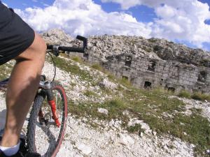 una persona che va in bicicletta di fronte a un muro di pietra di Club Hotel Alpino a Folgaria