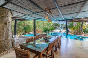 ein Esszimmer mit einem Tisch, Stühlen und einem Pool in der Unterkunft Tequila Sunrise Beach Villa-Diani Beach in Diani Beach