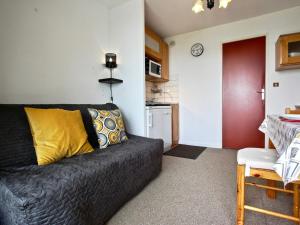 ein Wohnzimmer mit einem schwarzen Sofa und einer Küche in der Unterkunft Studio Chamrousse, 1 pièce, 6 personnes - FR-1-340-208 in Chamrousse