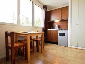 a kitchen with a wooden table and chairs and a kitchen with a stove at Studio Chamrousse, 1 pièce, 3 personnes - FR-1-340-109 in Chamrousse