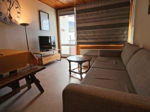 a living room with a couch and a table and a clock at Appartement Chamrousse, 2 pièces, 6 personnes - FR-1-340-147 in Chamrousse