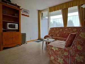 a living room with a couch and a tv at Studio Chamrousse, 1 pièce, 3 personnes - FR-1-340-135 in Chamrousse