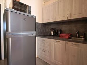 uma cozinha com um frigorífico de aço inoxidável e armários de madeira em Studio Chamrousse, 1 pièce, 4 personnes - FR-1-340-91 em Chamrousse