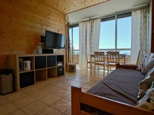 a living room with a bed and a flat screen tv at Studio Chamrousse, 1 pièce, 4 personnes - FR-1-549-22 in Chamrousse