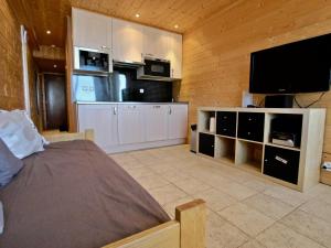 a bedroom with a bed and a flat screen tv at Studio Chamrousse, 1 pièce, 4 personnes - FR-1-549-22 in Chamrousse