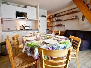 a dining room table with chairs and a kitchen at Appartement Chamrousse, 2 pièces, 7 personnes - FR-1-340-229 in Chamrousse