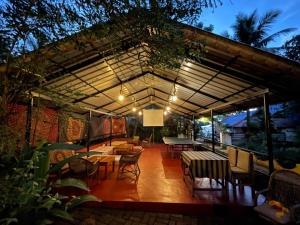 a patio with tables and chairs under a roof at The Lost Hostel, Varkala - Helipad in Varkala