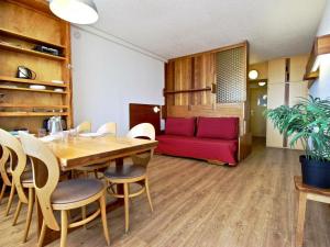 ein Wohnzimmer mit einem Tisch und einem roten Sofa in der Unterkunft Studio Chamrousse, 1 pièce, 4 personnes - FR-1-549-38 in Chamrousse