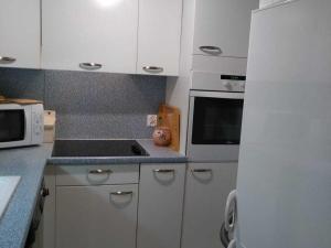 a kitchen with white cabinets and a stove top oven at Appartement Chamrousse, 2 pièces, 6 personnes - FR-1-549-54 in Chamrousse