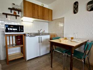 尚魯斯的住宿－Studio Chamrousse, 1 pièce, 3 personnes - FR-1-549-35，厨房配有桌子和白色冰箱。