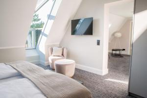 a bedroom with a bed and a chair and a tv at Boutique Hotel Gezeiten SPO in Sankt Peter-Ording