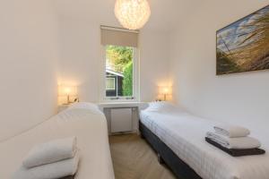 2 Betten in einem weißen Zimmer mit Fenster in der Unterkunft Oosterpark 76 - Oostkapelle in Oostkapelle