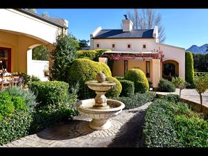 a fountain in a garden in front of a house at Petit & Grande Plaisir luxury self-catering in Franschhoek