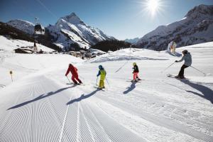 un grupo de personas esquiando por una pista cubierta de nieve en Lechquell Hotel Post, en Steeg