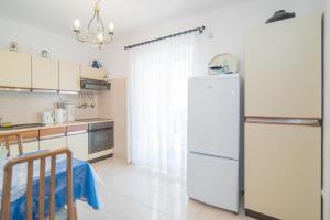 a kitchen with a white refrigerator and a table at Apartments Paco in Postira