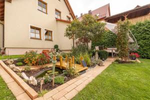 einen Garten mit einer Bank und Blumen vor einem Haus in der Unterkunft Gästezimmer Klein in Heiligenstadt