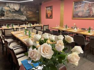 un gruppo di tavoli con rose bianche in una stanza di MADONCA ROOMS & RESTAURANT a Nova Gorica