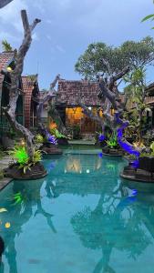 a pool in front of a house with trees in the water at Villa Telaga Wana in Sukawati