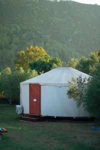 ein großes weißes Zelt mit einer roten Tür auf einem Feld in der Unterkunft Yol Glamping in Kayakoy