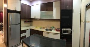 uma cozinha com armários brancos e um frigorífico preto em Stay N rest sweet home 185 em Seremban